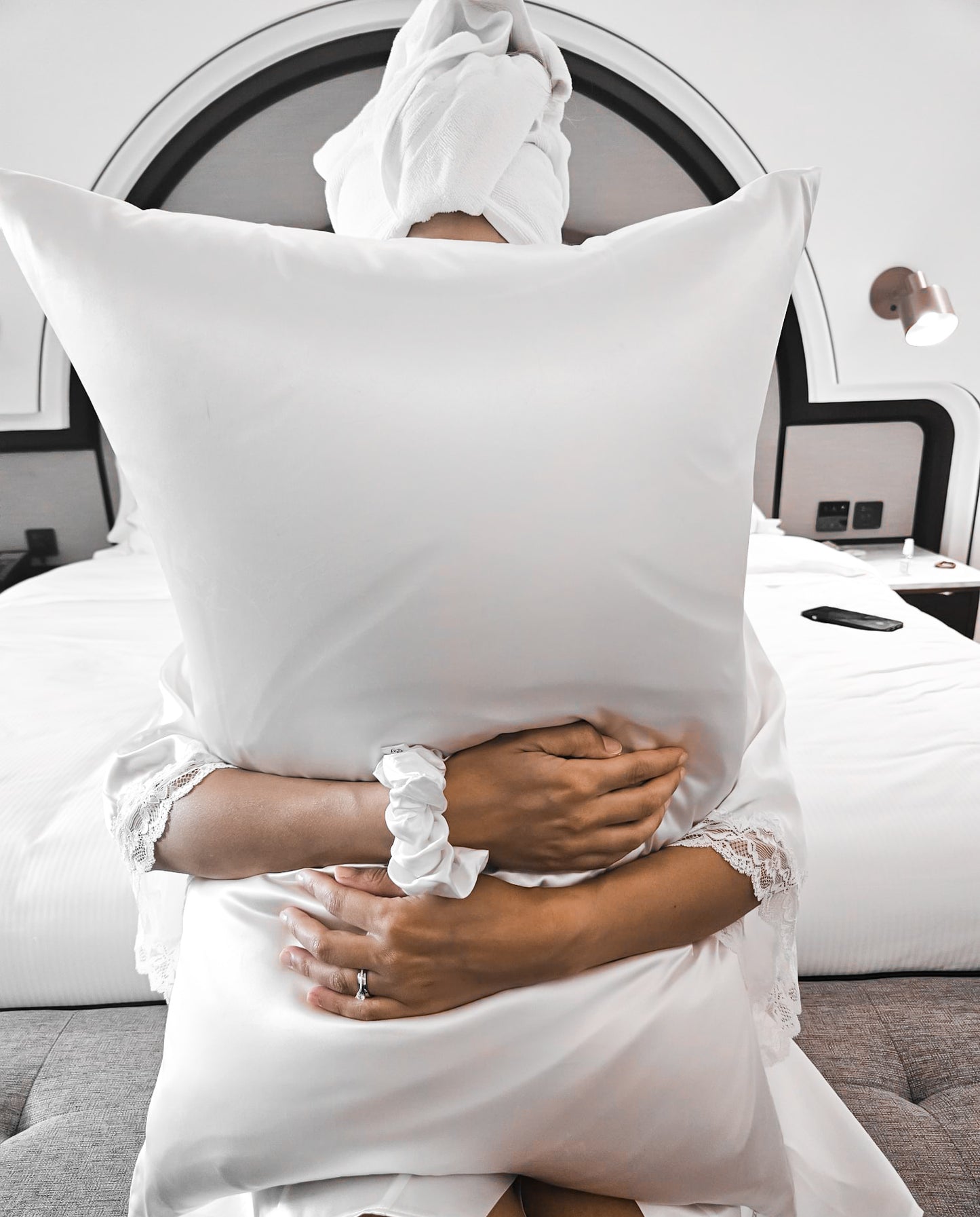 Model hugging silk pillowcase in ivory and scrunchie in hotel